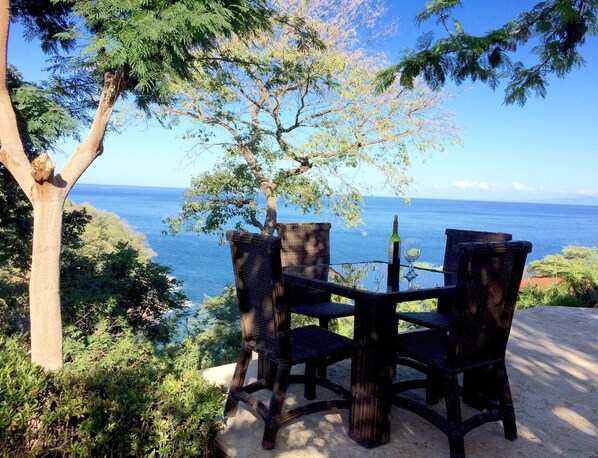 A table and chairs set outdoors with a view of the ocean.