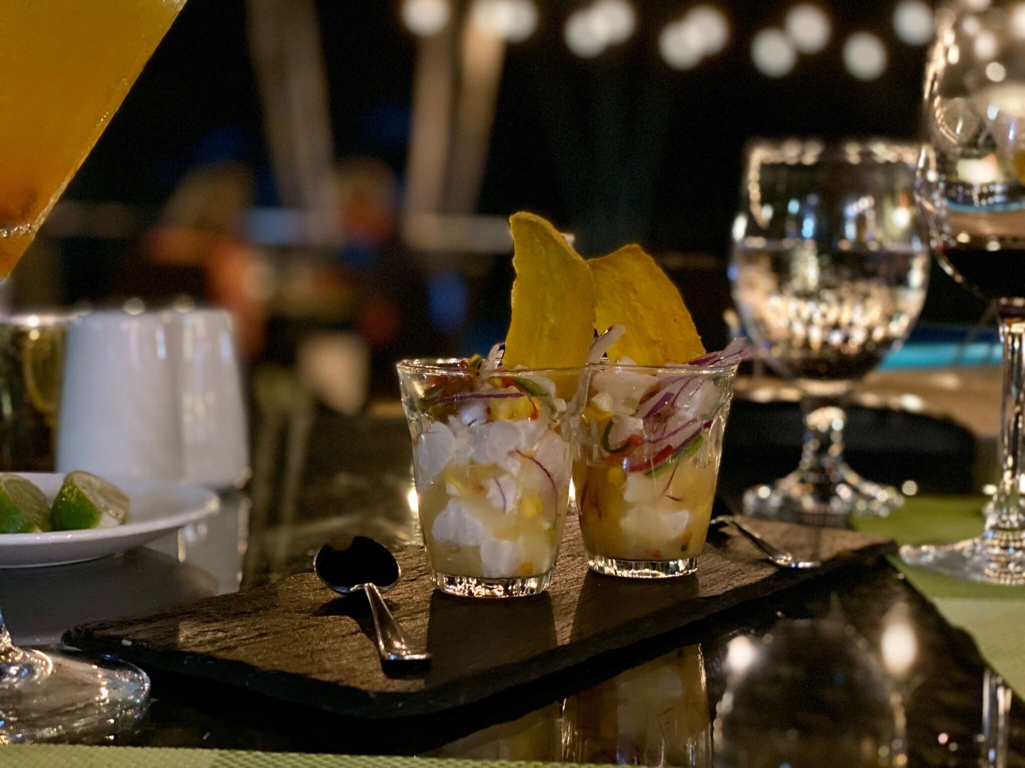 Un bar avec deux verres de cocktail, un quartier de citron vert et une cuillère, le tout posé sur un plateau en bois.