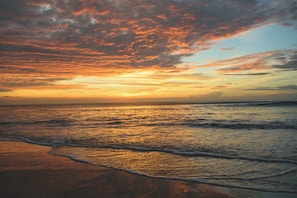 Une plage avec des vagues et un ciel au coucher du soleil.