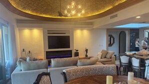 Een moderne woonkamer met een modulaire bank, een flatscreen televisie en een eethoek met een ronde tafel.