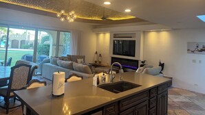 Een moderne keuken met een centraal kookeiland, ingebouwde apparatuur en een groot raam met uitzicht op de omgeving.