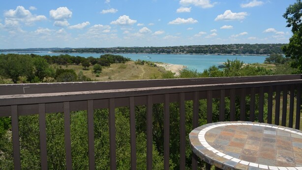 A balcony with a view of a coastal landscape, including a body of water and distant land. - Lake Travis Retreat - Water View (Leander)