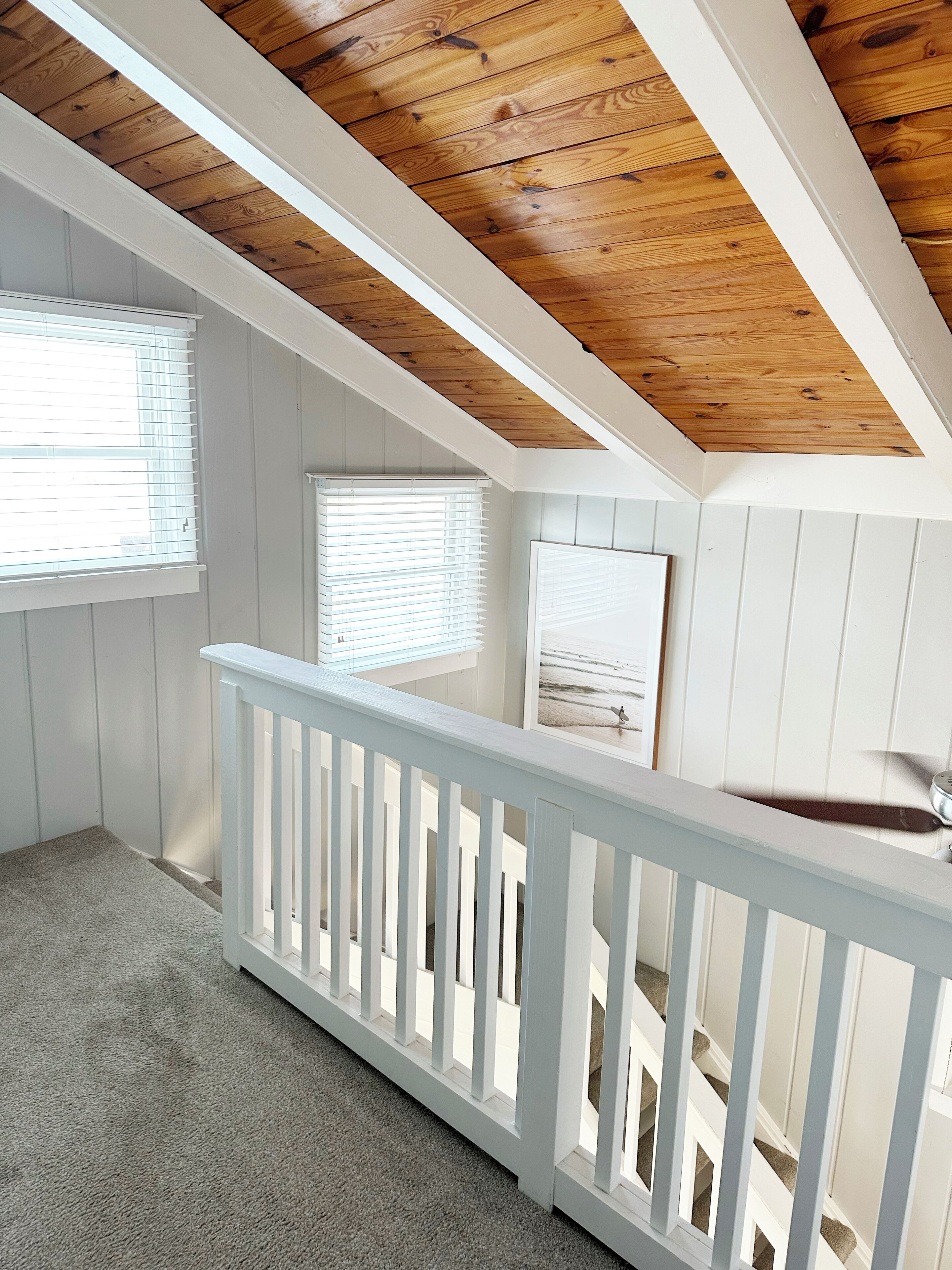 Una habitación con techo inclinado, paredes blancas y suelo de madera.
