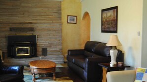 A living room with a fireplace, leather sofa, and a small round table.