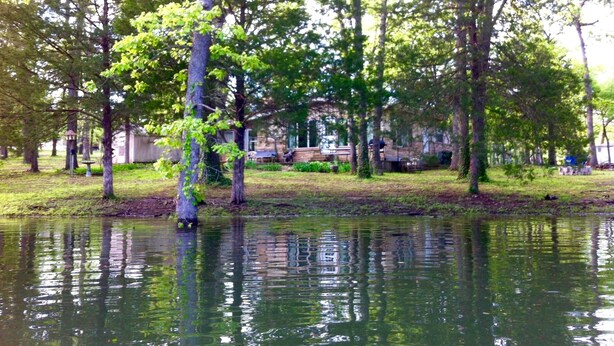 A tranquil park with a pond, trees, and a building in the background.