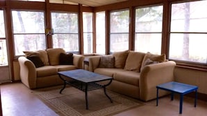A living room with two beige sofas, a coffee table, and a small blue table.