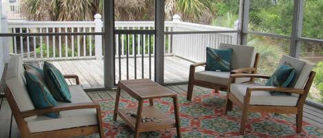Un espacio de estar techado al aire libre con muebles de madera y un tapete estampado.
