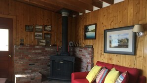 A cozy room with a brick fireplace, a red sofa, and a white table.