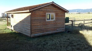 Una pequeña cabaña de madera con techo inclinado, una ventana y una puerta.