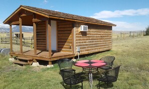 Una cabaña de madera con un porche y una pequeña mesa con sillas.