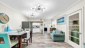 A spacious kitchen with white cabinets, a dining area with teal chairs, and a living room with a green sofa. - Longboat Key bliss. A perfect Retreat at Cabana Beach Club #9.Also available#8  (Longboat Key)