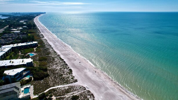 An aerial view of a coastal hotel with a long beachfront, clear blue water, and a well-maintained sandy beach. - Longboat Key bliss. A perfect Retreat at Cabana Beach Club #9.Also available#8  (Longboat Key)