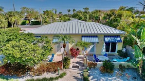 A house with a tiled roof, a front porch with blue chairs, and a small patio area. - Longboat Key bliss. A perfect Retreat at Cabana Beach Club #9.Also available#8  (Longboat Key)
