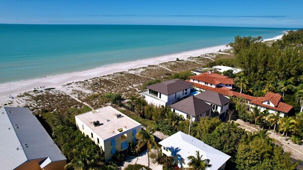 A coastal property with multiple buildings, a beach, and a clear view of the ocean.