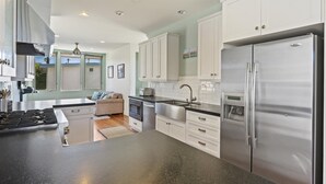 Una cocina moderna con armarios blancos, electrodomésticos de acero inoxidable y encimera negra.
