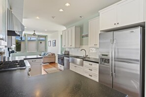 A modern kitchen with white cabinets, stainless steel appliances, and a black countertop.