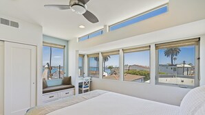 Un dormitorio con una cama grande, un escritorio y vistas a la ciudad a través de amplios ventanales.
