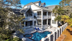 A two-story house with a swimming pool, a balcony, and a fenced deck area. - Ocean View, 3-Patio, 6BR, 6300sf Home w/Pool; 50 Steps to Beach, Coligny Circle! (Hilton Head Isalnd)