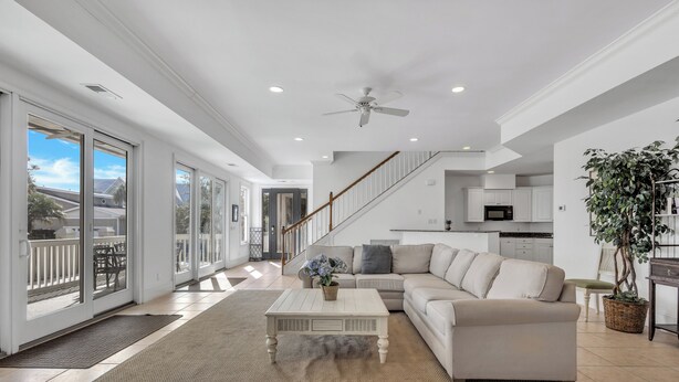A spacious living room with a large sectional sofa, a coffee table, and a staircase leading to an upper level. - Ocean View, 3-Patio, 6BR, 6300sf Home w/Pool; 50 Steps to Beach, Coligny Circle! (Hilton Head Isalnd)