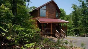 A wooden cabin with a porch and stairs, surrounded by dense greenery. - A Bear's Kind of Fun in Pigeon Forge #unforgettable 4 bedroom w/ Games & Full Theater! (Sevierville)