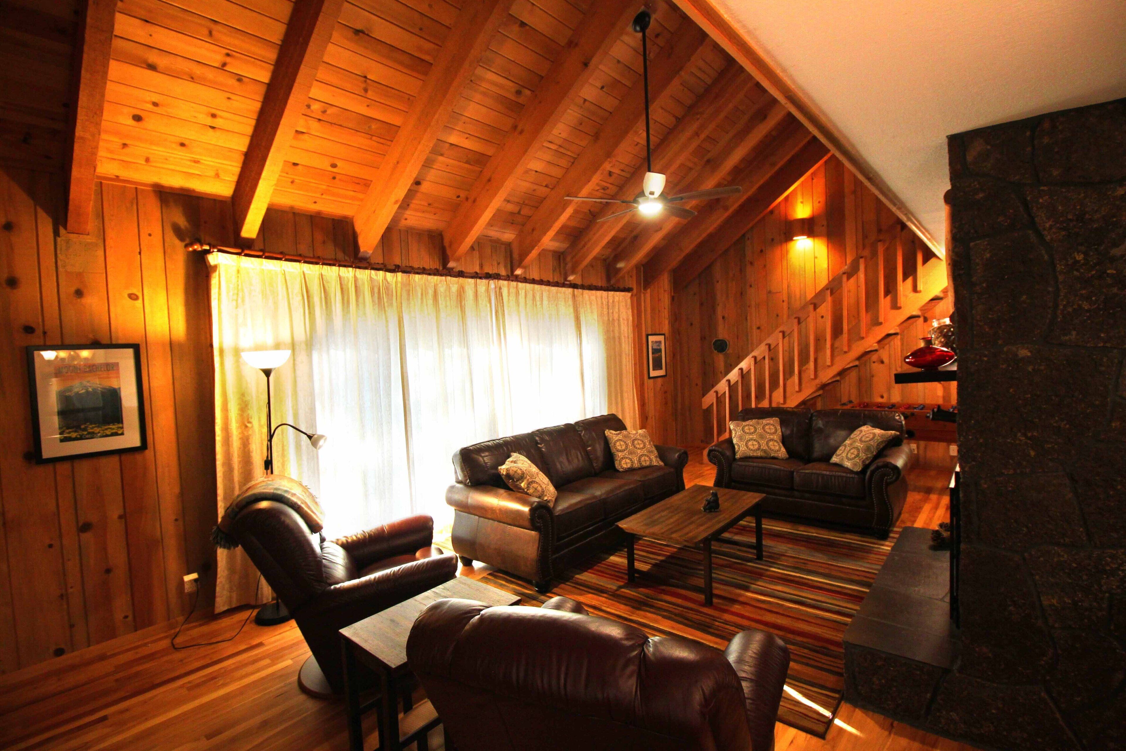 Un interior acogedor de madera con un sofá de cuero, una mesa de centro y una chimenea.