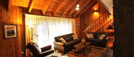 Un interior acogedor de madera con un sofá de cuero, una mesa de centro y una chimenea.
