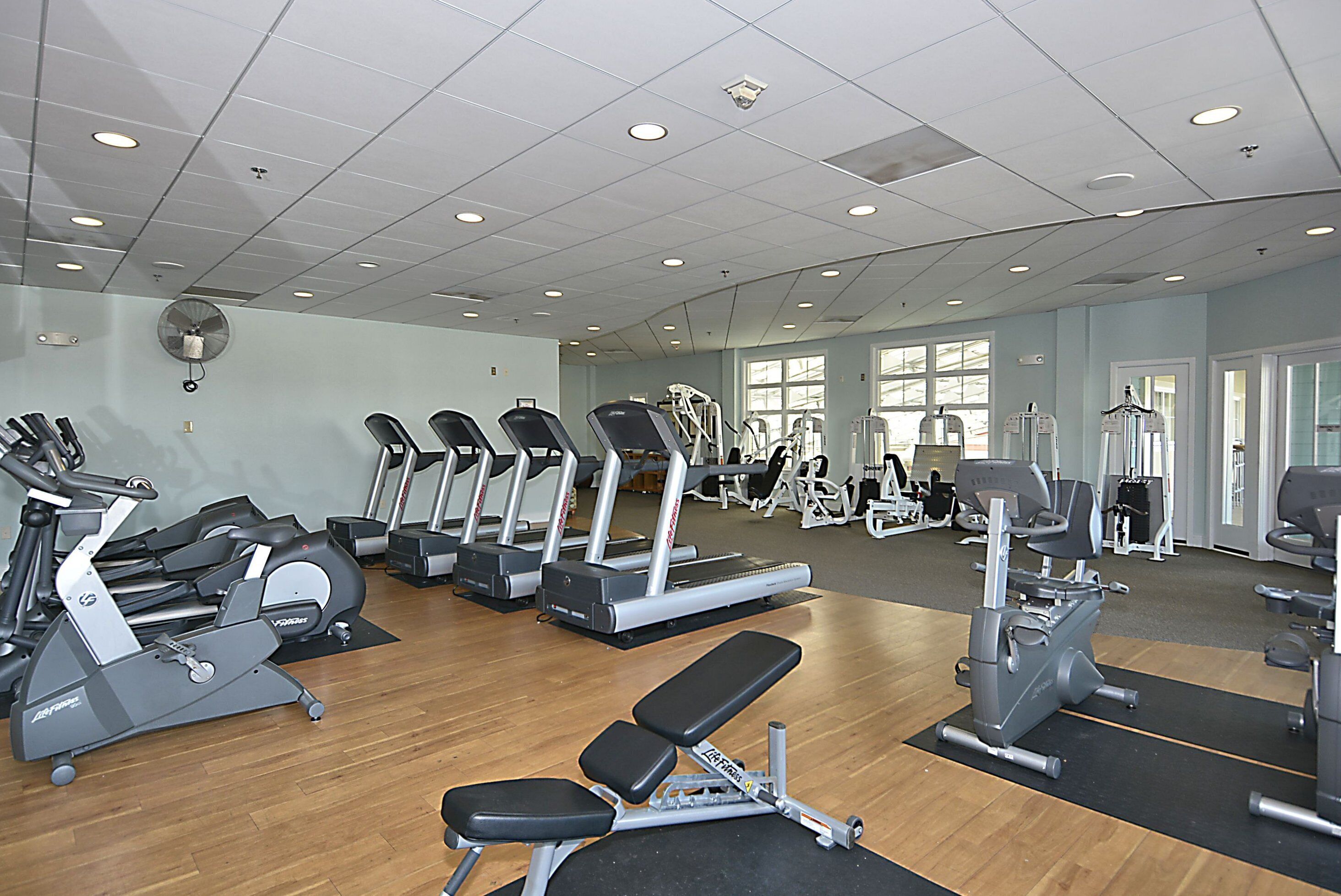 Un gimnasio con diversos equipos de ejercicio, incluyendo cintas de correr, bicicletas estáticas y máquinas de pesas.