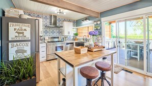 Una cucina moderna con travi in legno, un'isola centrale con sgabelli e vista su un patio esterno.