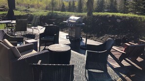 Un patio al aire libre con mobiliario de mimbre, una parrilla y vistas a un paisaje montañoso.