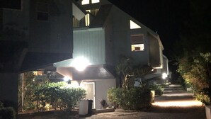 Une maison à deux étages, dotée d’un toit en pente et d’un escalier apparent menant à l’étage supérieur.