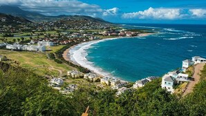 Une ville côtière avec une plage, des maisons et une montagne en arrière-plan.