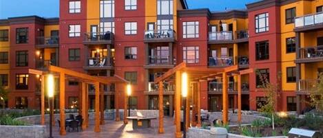 A multi-story hotel with a courtyard, outdoor seating, and a barbecue grill.