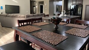 Een moderne keuken met donkere kastjes, een roestvrijstalen koelkast en een eethoek met een houten tafel en stoelen.