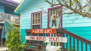A turquoise building with a sign reading "The Dancing Dunes" and "Port Aransas Texas". - The Shell Cabin is a place to relax and enjoy the beach! (Port Aransas)
