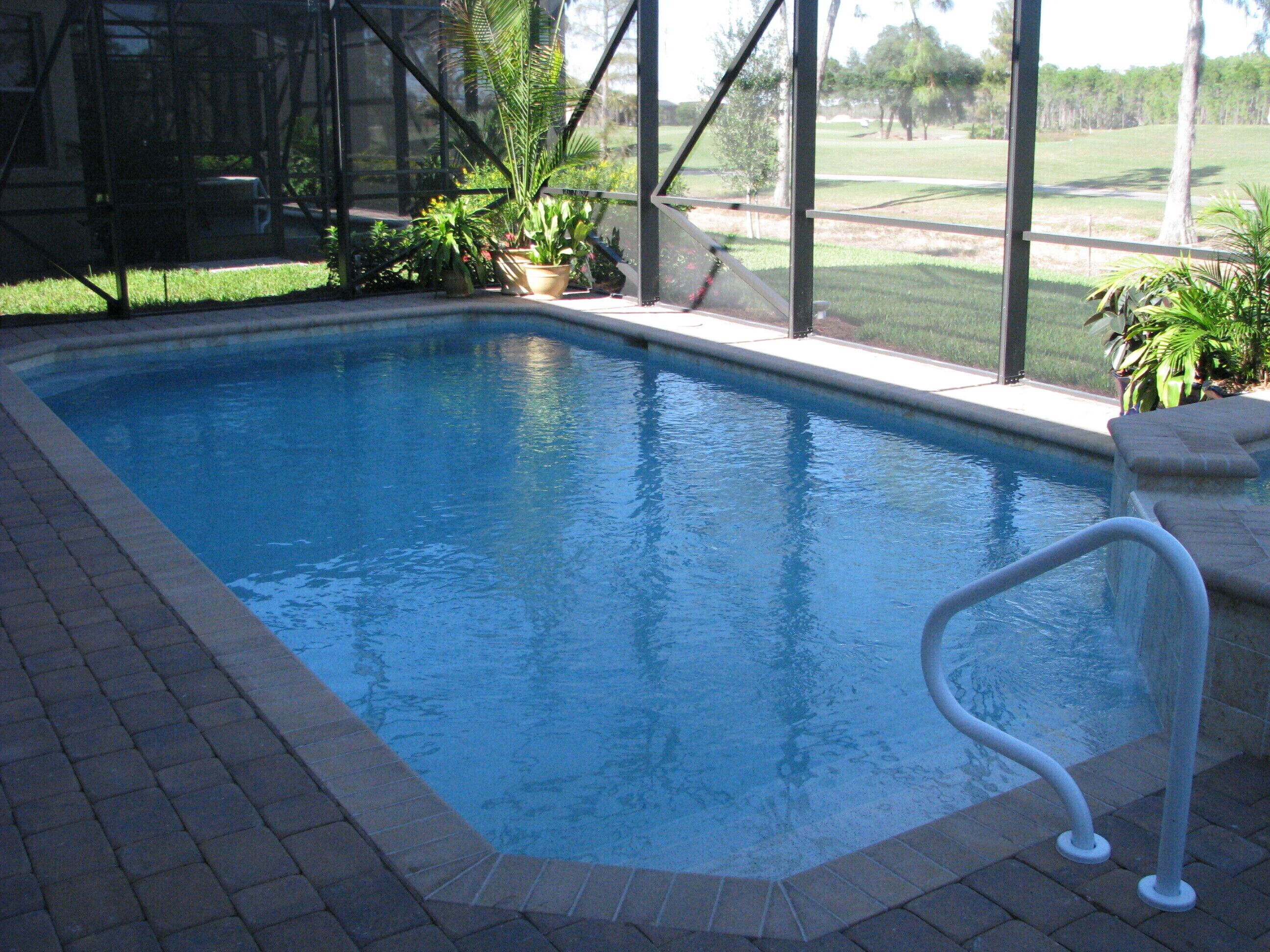 An indoor swimming pool with a clear view of the surrounding landscape through large windows.