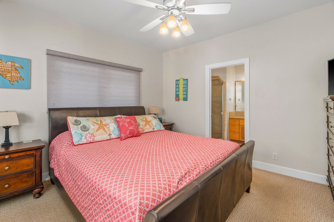 Un dormitorio con cama, mesita de noche, cómoda y ventilador de techo.