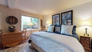 A bedroom with a large bed, wooden dresser, and a window with a view of greenery. - Vail Trails Studio | 3B - Studio Platinum (Vail)