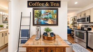 Your inviting coffee and tea station awaits on a rustic wooden table, complete with a stylish dispenser, fresh mugs, and charming décor—perfect for leisurely mornings.