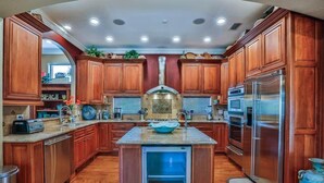 A kitchen with wooden cabinets, a central island, a built-in oven, and a refrigerator. - Casa Bahari W/Private Pool 5-Bed/Pool/Spa/Lux Amenities (Destin)