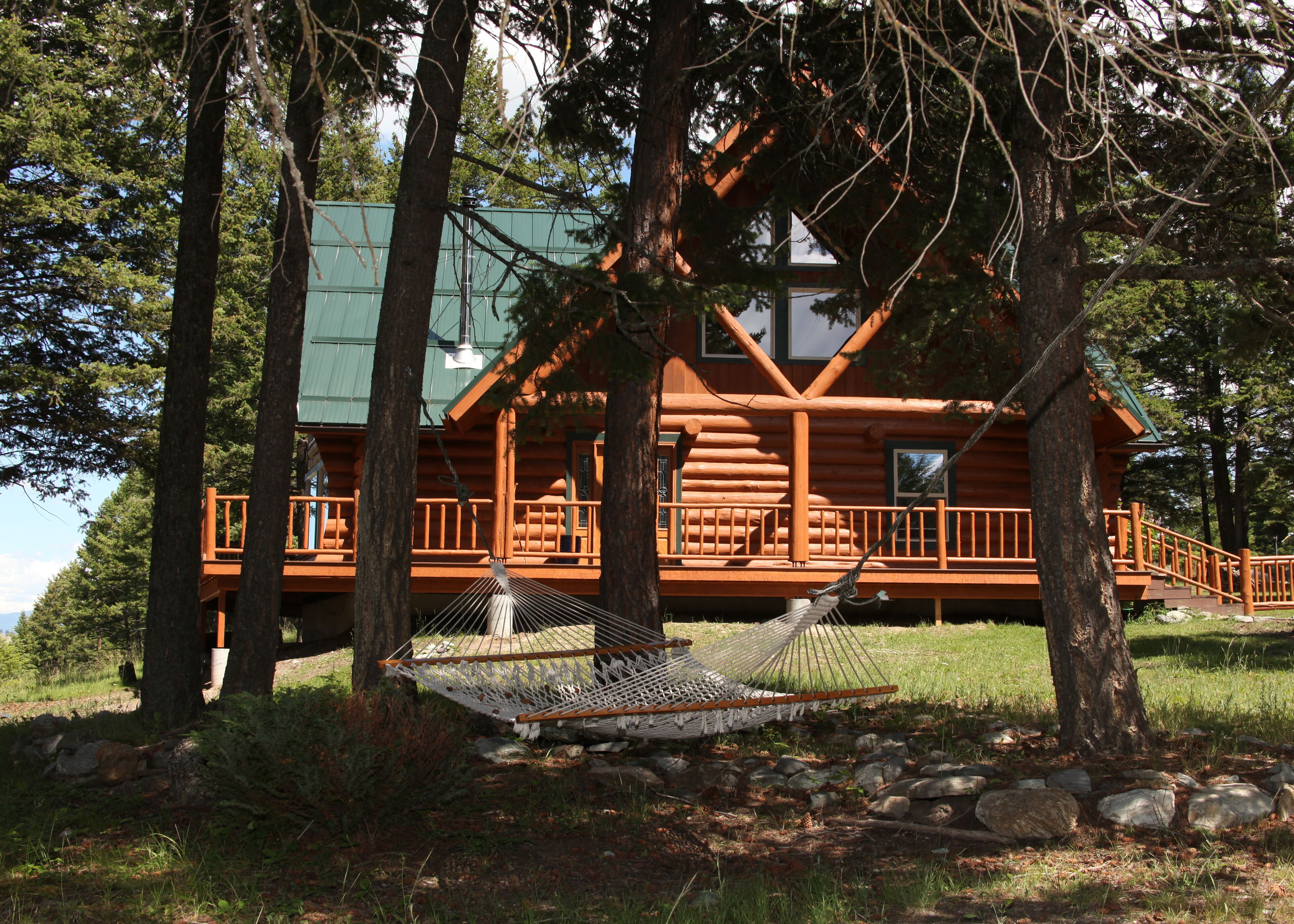 A log cabin with a deck and a hammock.