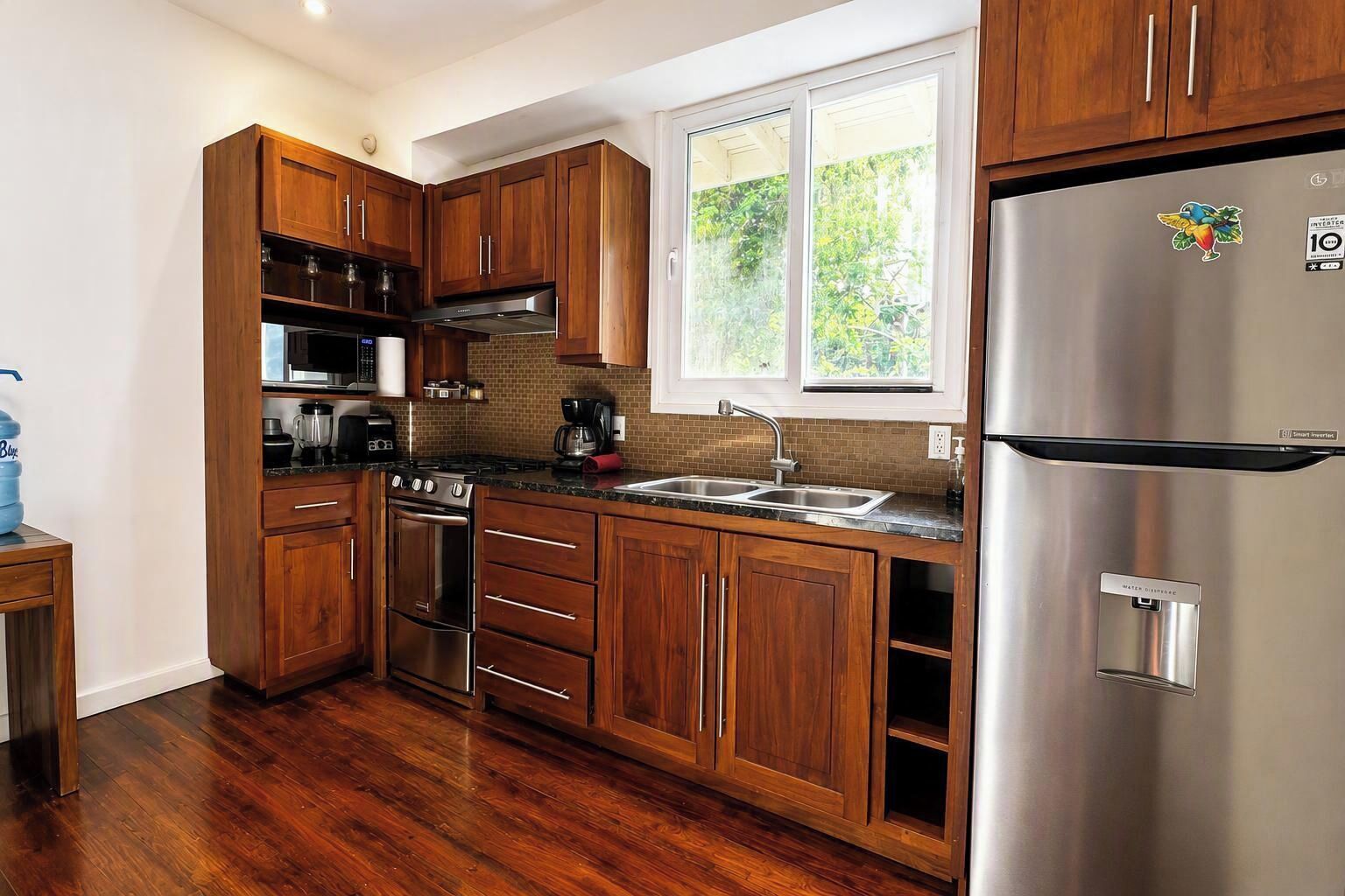 A modern kitchen with wooden cabinets, stainless steel appliances, and a large window providing natural light.