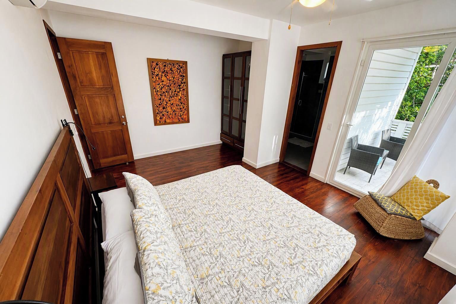 Un dormitorio con una cama, una puerta de madera, una puerta de cristal y vistas al exterior.