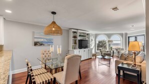 A spacious living area with a dining table, chairs, a sofa, and a TV in the background. - "Sea Escape" ~ Fully Renovated ~ Beach Gear credit included ~ Pool Access (Isle of Palms)