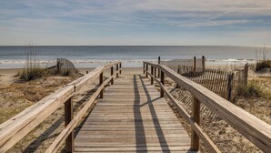 A wooden boardwalk leading to a beach with a fence on one side and a wooden fence on the other. - "Sea Escape" ~ Fully Renovated ~ Beach Gear credit included ~ Pool Access (Isle of Palms)