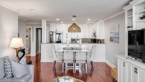 A modern kitchen with white cabinets, a central island, and a hanging light fixture. - "Sea Escape" ~ Fully Renovated ~ Beach Gear credit included ~ Pool Access (Isle of Palms)