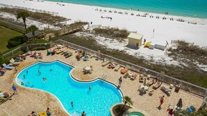 Un espace piscine avec vue sur la plage, des chaises longues et un petit bâtiment.