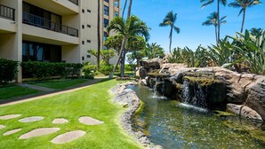 A hotel with a pool, palm trees, and a waterfall. - Sugar Beach Resort  - Ocean View,   (Off Season Special Rates) (Kihei)