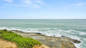 A coastal landscape with a rocky shoreline and clear blue sky.