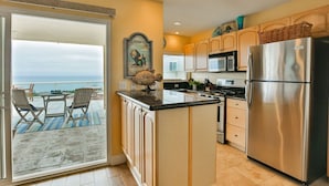 A kitchen with a large island, stainless steel appliances, and a view to the outside.