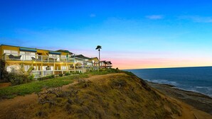 A coastal hotel with multiple buildings, a beach view, and a palm tree.